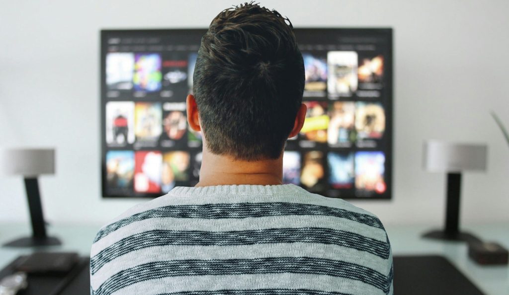 Man choosing from movies on TV. 