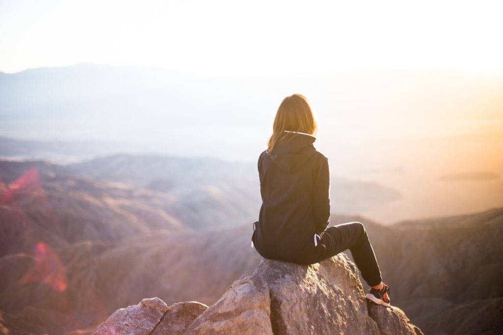 woman sitting on mountain looking at the horizon